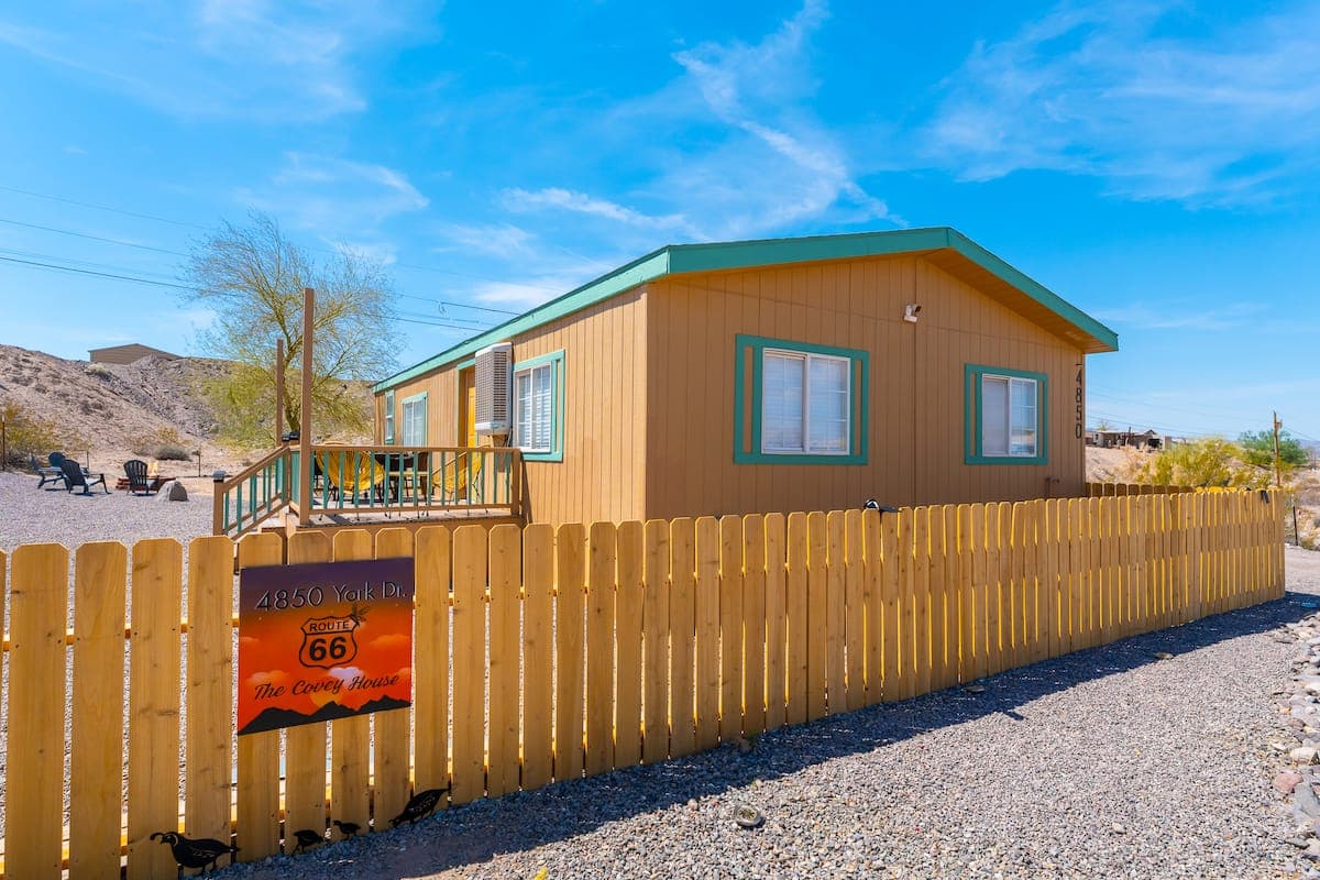 Topock Cozy Family Getaway exterior behind a wooden fence with desert mountains beyond
