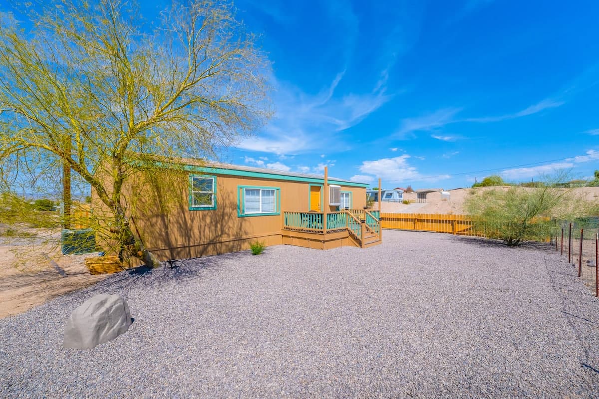 Sunny gravel yard beside the home and a shade tree