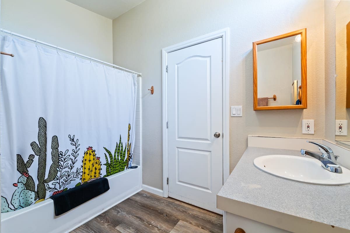 Bathroom vanity and shower with cactus-patterned curtain
